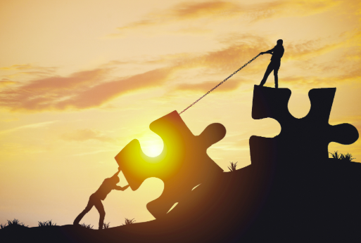 A piece of a puzzle being moved into place with teamwork